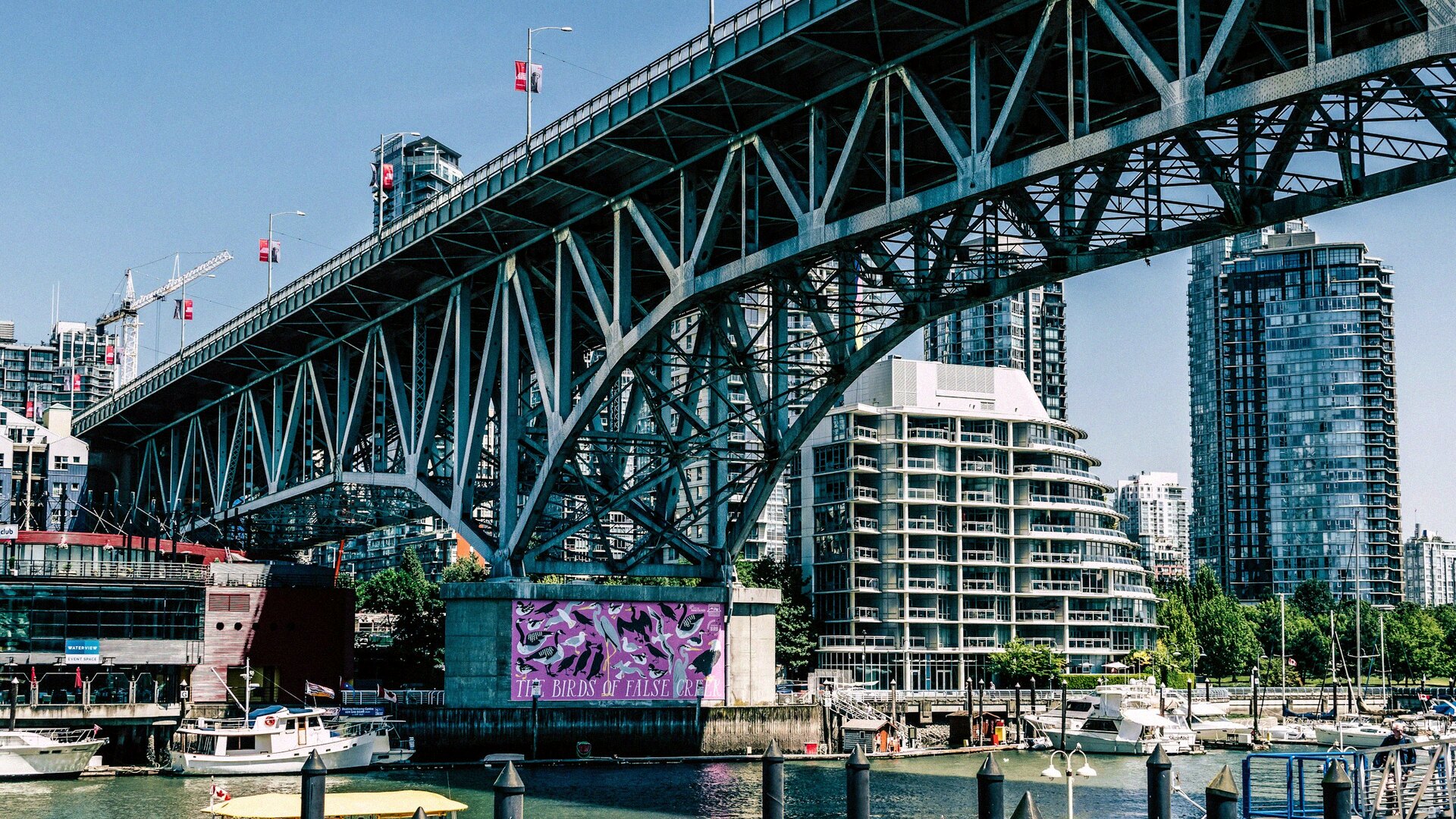 Granville Bridge arching over False Creek with downtown Vancouver towers and a marina underneath