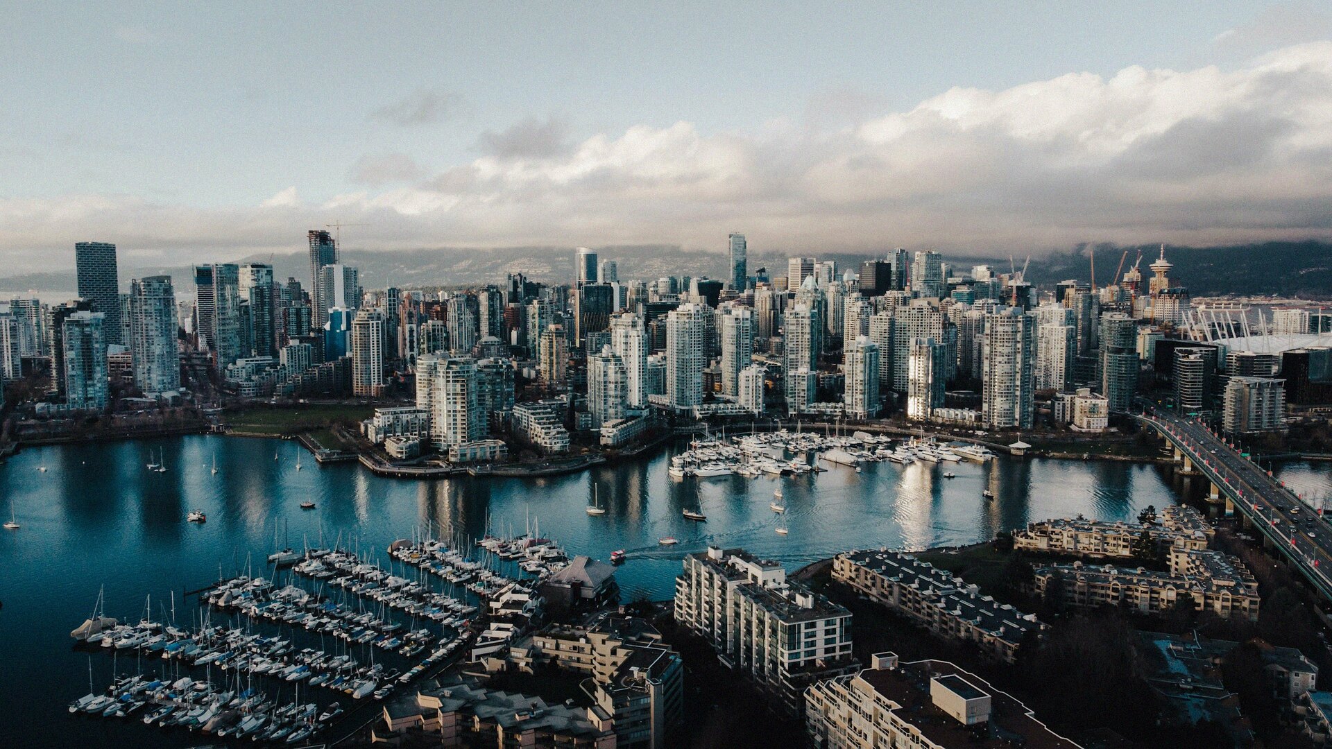 Aerial view of downtown Vancouver and False Creek marinas at dusk with the North Shore mountains in the distance