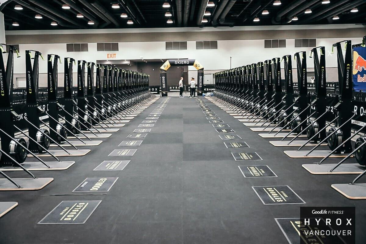 Rows of SkiErgs lined up on the HYROX Vancouver competition floor before racing starts
