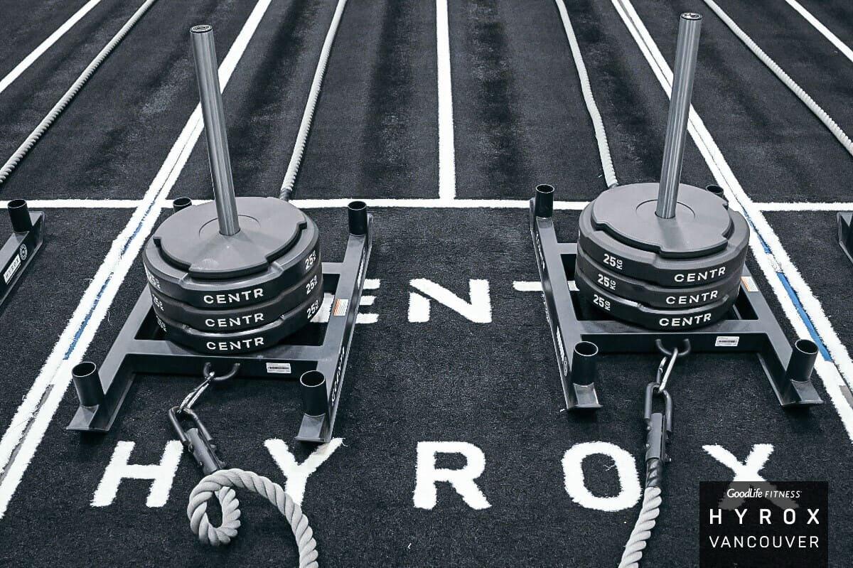 Two loaded HYROX sleds waiting on the marked sled lanes at HYROX Vancouver